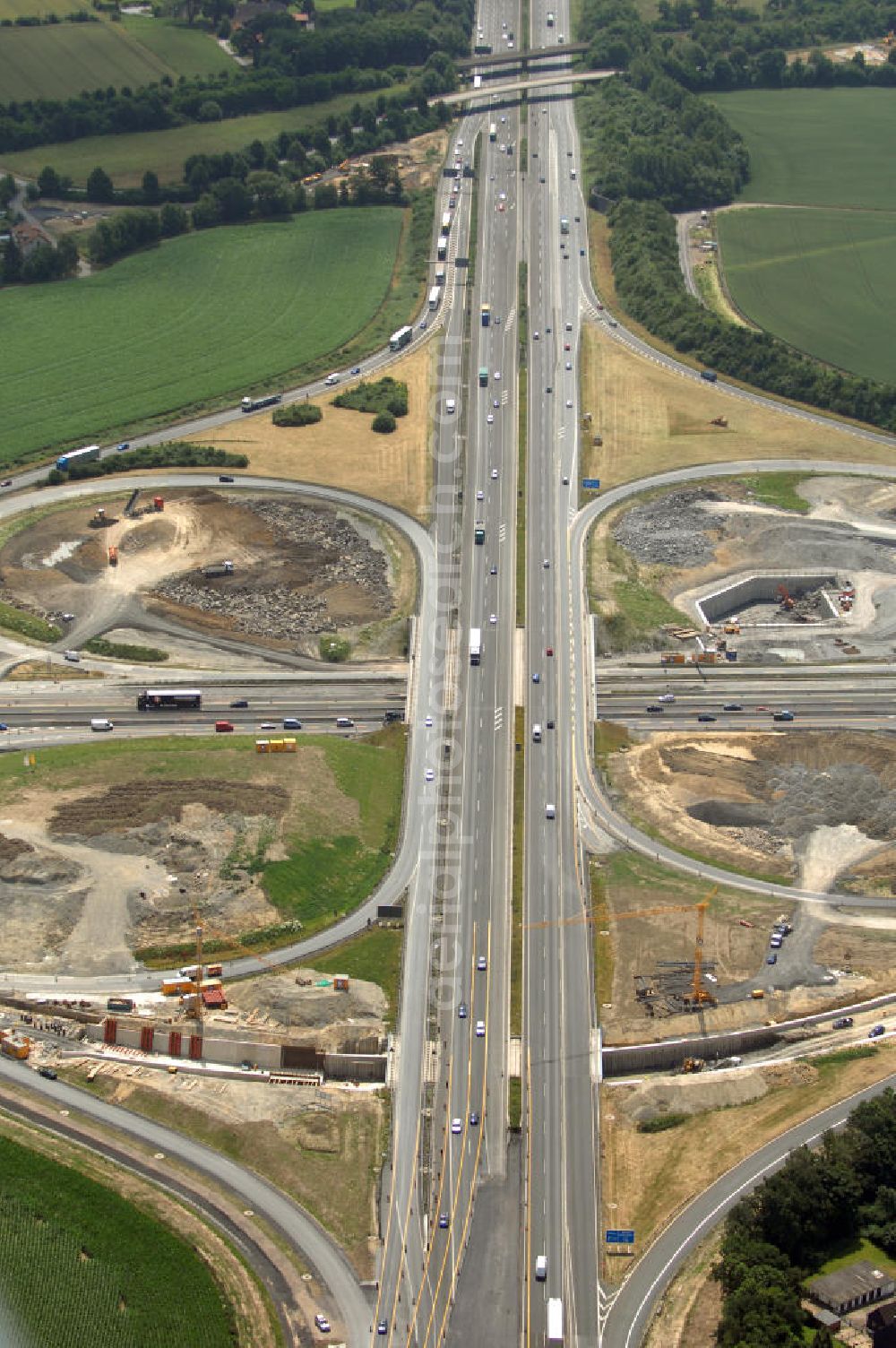 KAMEN from above - Das Kamener Kreuz ist das zweiteälteste Autobahnkreuz in Kleeblattform Deutschlands und dient der Verbindung der ersten Autobahnen des Landes, der A 1 (Nord-Süd-Richtung) und der A 2 (Ost-West-Richtung). Seine Einweihung fand 1937 statt. Das Autobahnkreuz liegt im Nordosten des Ruhrgebiets bei Kamen und Bergkamen zwischen den Großstädten Dortmund und Hamm und ist auch aufgrund der hier aufeinan dertreffenden wichtigen Verkehrsachsen ein überaus stark befahrener Verkehrsknotenpunkt. Die meisten Autofahrer kennen das Kamener Kreuz über die Staumeldungen der Verkehrsrundfunksender. Das Kamener Kreuz wird täglich von 160.000 Fahrzeugen befahren. Zur Zeit wird das Kamener Kreuz ausgebaut. Die Fertigstellung soll Ende 2009 sein. Das Kreuz wird dann von allen Seiten sechsspurig zu befahren sein. Eine besondere Herausforderung hierbei ist der Abriss und komplette Neubau der A 1-Brücke, die täglich von 90.000 Fahrzeugen befahren wird. Das Kreuz wird dann seine klassische Kleeblattform verlieren, da der Verkehr von der A 2 aus Richtung Hannover über eine Rampe auf die A 1 in Richtung Köln geleitet wird. Ausführende Firmen sind OEVERMANN, Münster Verkehrswegebau und Schäfer