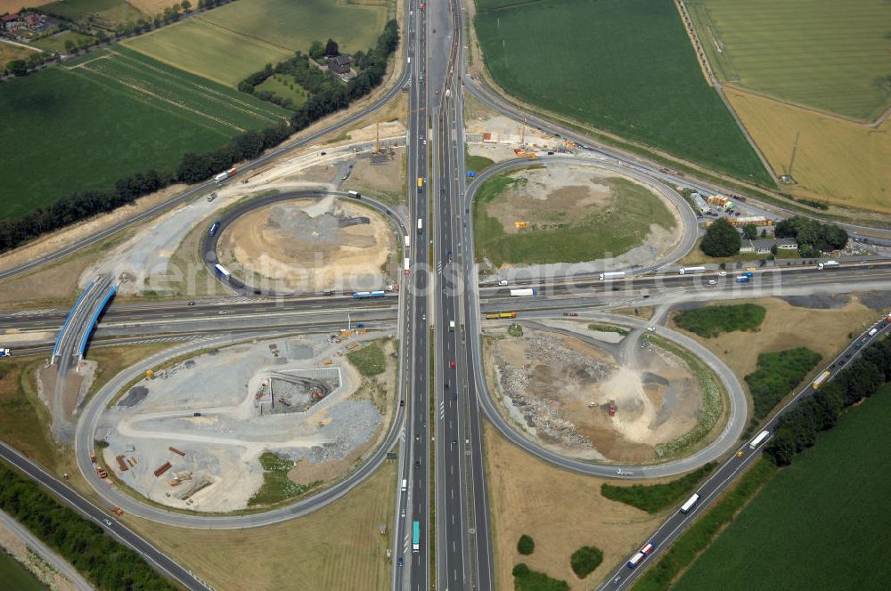 KAMEN from above - Das Kamener Kreuz ist das zweiteälteste Autobahnkreuz in Kleeblattform Deutschlands und dient der Verbindung der ersten Autobahnen des Landes, der A 1 (Nord-Süd-Richtung) und der A 2 (Ost-West-Richtung). Seine Einweihung fand 1937 statt. Das Autobahnkreuz liegt im Nordosten des Ruhrgebiets bei Kamen und Bergkamen zwischen den Großstädten Dortmund und Hamm und ist auch aufgrund der hier aufeinan dertreffenden wichtigen Verkehrsachsen ein überaus stark befahrener Verkehrsknotenpunkt. Die meisten Autofahrer kennen das Kamener Kreuz über die Staumeldungen der Verkehrsrundfunksender. Das Kamener Kreuz wird täglich von 160.000 Fahrzeugen befahren. Zur Zeit wird das Kamener Kreuz ausgebaut. Die Fertigstellung soll Ende 2009 sein. Das Kreuz wird dann von allen Seiten sechsspurig zu befahren sein. Eine besondere Herausforderung hierbei ist der Abriss und komplette Neubau der A 1-Brücke, die täglich von 90.000 Fahrzeugen befahren wird. Das Kreuz wird dann seine klassische Kleeblattform verlieren, da der Verkehr von der A 2 aus Richtung Hannover über eine Rampe auf die A 1 in Richtung Köln geleitet wird. Ausführende Firmen sind OEVERMANN, Münster Verkehrswegebau und Schäfer