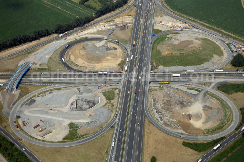 KAMEN from the bird's eye view: Das Kamener Kreuz ist das zweiteälteste Autobahnkreuz in Kleeblattform Deutschlands und dient der Verbindung der ersten Autobahnen des Landes, der A 1 (Nord-Süd-Richtung) und der A 2 (Ost-West-Richtung). Seine Einweihung fand 1937 statt. Das Autobahnkreuz liegt im Nordosten des Ruhrgebiets bei Kamen und Bergkamen zwischen den Großstädten Dortmund und Hamm und ist auch aufgrund der hier aufeinan dertreffenden wichtigen Verkehrsachsen ein überaus stark befahrener Verkehrsknotenpunkt. Die meisten Autofahrer kennen das Kamener Kreuz über die Staumeldungen der Verkehrsrundfunksender. Das Kamener Kreuz wird täglich von 160.000 Fahrzeugen befahren. Zur Zeit wird das Kamener Kreuz ausgebaut. Die Fertigstellung soll Ende 2009 sein. Das Kreuz wird dann von allen Seiten sechsspurig zu befahren sein. Eine besondere Herausforderung hierbei ist der Abriss und komplette Neubau der A 1-Brücke, die täglich von 90.000 Fahrzeugen befahren wird. Das Kreuz wird dann seine klassische Kleeblattform verlieren, da der Verkehr von der A 2 aus Richtung Hannover über eine Rampe auf die A 1 in Richtung Köln geleitet wird. Ausführende Firmen sind OEVERMANN, Münster Verkehrswegebau und Schäfer