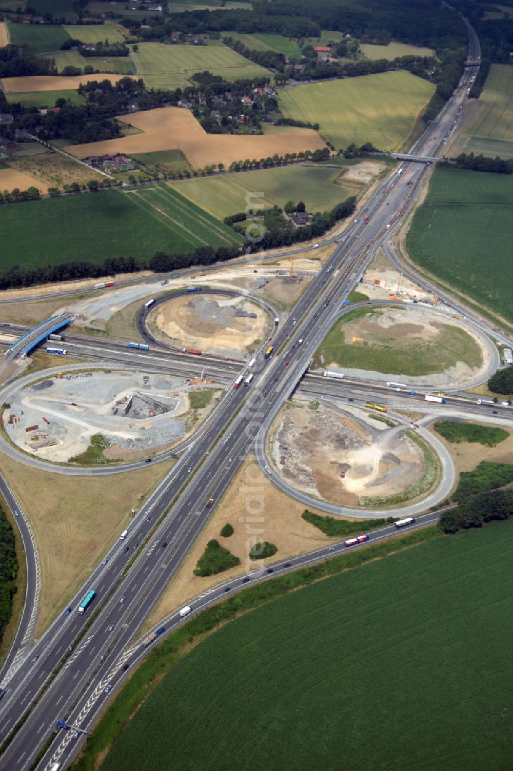 Aerial image KAMEN - Das Kamener Kreuz ist das zweiteälteste Autobahnkreuz in Kleeblattform Deutschlands und dient der Verbindung der ersten Autobahnen des Landes, der A 1 (Nord-Süd-Richtung) und der A 2 (Ost-West-Richtung). Seine Einweihung fand 1937 statt. Das Autobahnkreuz liegt im Nordosten des Ruhrgebiets bei Kamen und Bergkamen zwischen den Großstädten Dortmund und Hamm und ist auch aufgrund der hier aufeinan dertreffenden wichtigen Verkehrsachsen ein überaus stark befahrener Verkehrsknotenpunkt. Die meisten Autofahrer kennen das Kamener Kreuz über die Staumeldungen der Verkehrsrundfunksender. Das Kamener Kreuz wird täglich von 160.000 Fahrzeugen befahren. Zur Zeit wird das Kamener Kreuz ausgebaut. Die Fertigstellung soll Ende 2009 sein. Das Kreuz wird dann von allen Seiten sechsspurig zu befahren sein. Eine besondere Herausforderung hierbei ist der Abriss und komplette Neubau der A 1-Brücke, die täglich von 90.000 Fahrzeugen befahren wird. Das Kreuz wird dann seine klassische Kleeblattform verlieren, da der Verkehr von der A 2 aus Richtung Hannover über eine Rampe auf die A 1 in Richtung Köln geleitet wird. Ausführende Firmen sind OEVERMANN, Münster Verkehrswegebau und Schäfer