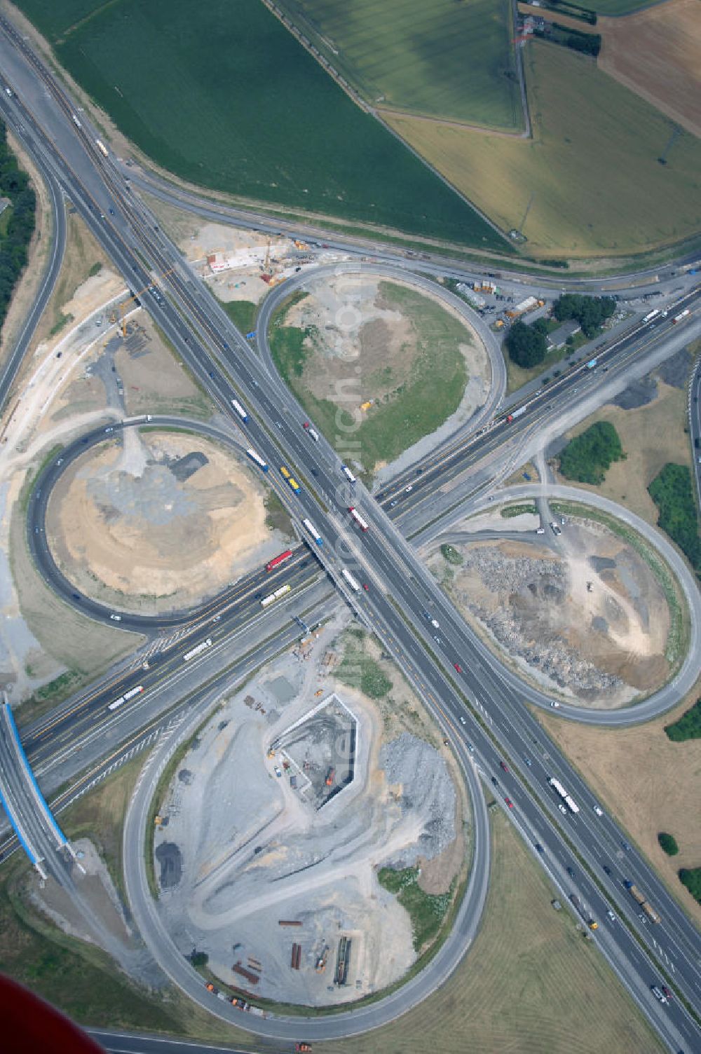 KAMEN from the bird's eye view: Das Kamener Kreuz ist das zweiteälteste Autobahnkreuz in Kleeblattform Deutschlands und dient der Verbindung der ersten Autobahnen des Landes, der A 1 (Nord-Süd-Richtung) und der A 2 (Ost-West-Richtung). Seine Einweihung fand 1937 statt. Das Autobahnkreuz liegt im Nordosten des Ruhrgebiets bei Kamen und Bergkamen zwischen den Großstädten Dortmund und Hamm und ist auch aufgrund der hier aufeinan dertreffenden wichtigen Verkehrsachsen ein überaus stark befahrener Verkehrsknotenpunkt. Die meisten Autofahrer kennen das Kamener Kreuz über die Staumeldungen der Verkehrsrundfunksender. Das Kamener Kreuz wird täglich von 160.000 Fahrzeugen befahren. Zur Zeit wird das Kamener Kreuz ausgebaut. Die Fertigstellung soll Ende 2009 sein. Das Kreuz wird dann von allen Seiten sechsspurig zu befahren sein. Eine besondere Herausforderung hierbei ist der Abriss und komplette Neubau der A 1-Brücke, die täglich von 90.000 Fahrzeugen befahren wird. Das Kreuz wird dann seine klassische Kleeblattform verlieren, da der Verkehr von der A 2 aus Richtung Hannover über eine Rampe auf die A 1 in Richtung Köln geleitet wird. Ausführende Firmen sind OEVERMANN, Münster Verkehrswegebau und Schäfer