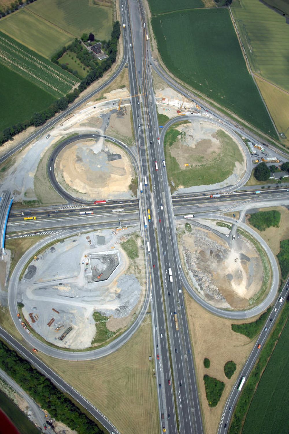 Aerial image KAMEN - Das Kamener Kreuz ist das zweiteälteste Autobahnkreuz in Kleeblattform Deutschlands und dient der Verbindung der ersten Autobahnen des Landes, der A 1 (Nord-Süd-Richtung) und der A 2 (Ost-West-Richtung). Seine Einweihung fand 1937 statt. Das Autobahnkreuz liegt im Nordosten des Ruhrgebiets bei Kamen und Bergkamen zwischen den Großstädten Dortmund und Hamm und ist auch aufgrund der hier aufeinan dertreffenden wichtigen Verkehrsachsen ein überaus stark befahrener Verkehrsknotenpunkt. Die meisten Autofahrer kennen das Kamener Kreuz über die Staumeldungen der Verkehrsrundfunksender. Das Kamener Kreuz wird täglich von 160.000 Fahrzeugen befahren. Zur Zeit wird das Kamener Kreuz ausgebaut. Die Fertigstellung soll Ende 2009 sein. Das Kreuz wird dann von allen Seiten sechsspurig zu befahren sein. Eine besondere Herausforderung hierbei ist der Abriss und komplette Neubau der A 1-Brücke, die täglich von 90.000 Fahrzeugen befahren wird. Das Kreuz wird dann seine klassische Kleeblattform verlieren, da der Verkehr von der A 2 aus Richtung Hannover über eine Rampe auf die A 1 in Richtung Köln geleitet wird. Ausführende Firmen sind OEVERMANN, Münster Verkehrswegebau und Schäfer