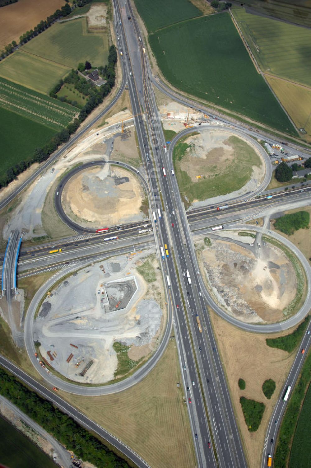 Aerial photograph KAMEN - Das Kamener Kreuz ist das zweiteälteste Autobahnkreuz in Kleeblattform Deutschlands und dient der Verbindung der ersten Autobahnen des Landes, der A 1 (Nord-Süd-Richtung) und der A 2 (Ost-West-Richtung). Seine Einweihung fand 1937 statt. Das Autobahnkreuz liegt im Nordosten des Ruhrgebiets bei Kamen und Bergkamen zwischen den Großstädten Dortmund und Hamm und ist auch aufgrund der hier aufeinan dertreffenden wichtigen Verkehrsachsen ein überaus stark befahrener Verkehrsknotenpunkt. Die meisten Autofahrer kennen das Kamener Kreuz über die Staumeldungen der Verkehrsrundfunksender. Das Kamener Kreuz wird täglich von 160.000 Fahrzeugen befahren. Zur Zeit wird das Kamener Kreuz ausgebaut. Die Fertigstellung soll Ende 2009 sein. Das Kreuz wird dann von allen Seiten sechsspurig zu befahren sein. Eine besondere Herausforderung hierbei ist der Abriss und komplette Neubau der A 1-Brücke, die täglich von 90.000 Fahrzeugen befahren wird. Das Kreuz wird dann seine klassische Kleeblattform verlieren, da der Verkehr von der A 2 aus Richtung Hannover über eine Rampe auf die A 1 in Richtung Köln geleitet wird. Ausführende Firmen sind OEVERMANN, Münster Verkehrswegebau und Schäfer