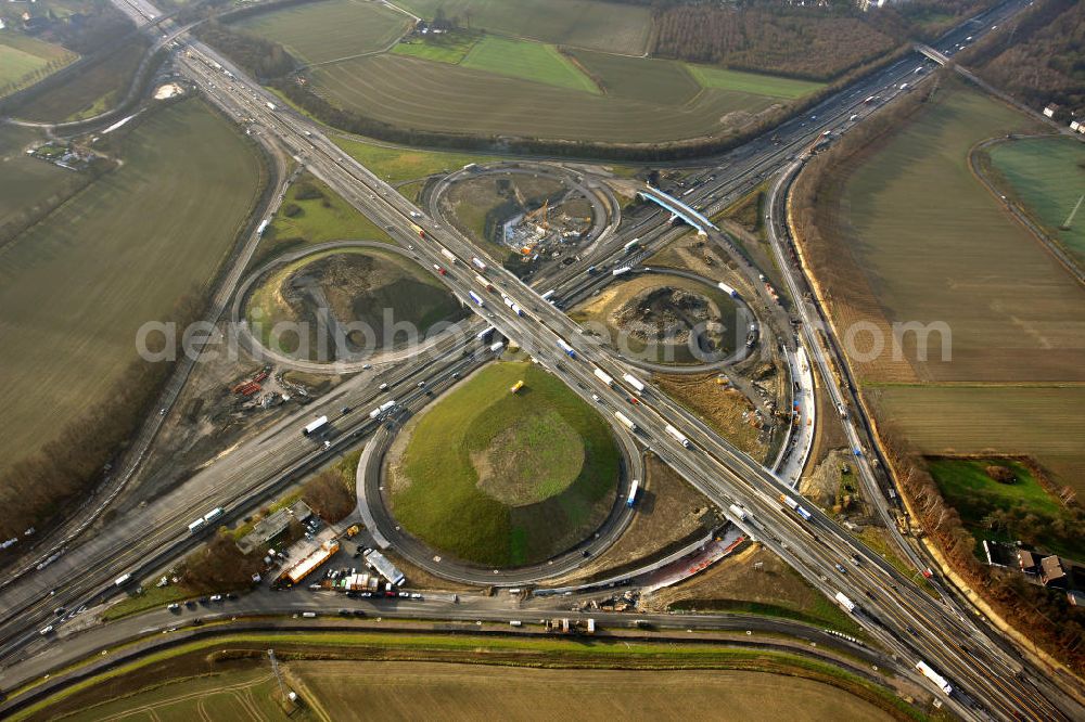 Aerial image Kamen - Das Kamener Kreuz ist das zweiteälteste Autobahnkreuz in Kleeblattform Deutschlands und dient der Verbindung der ersten Autobahnen des Landes, der A 1 (Nord-Süd-Richtung) und der A 2 (Ost-West-Richtung). Seine Einweihung fand 1937 statt. Das Autobahnkreuz liegt im Nordosten des Ruhrgebiets bei Kamen und Bergkamen zwischen den Großstädten Dortmund und Hamm und ist auch aufgrund der hier aufeinan dertreffenden wichtigen Verkehrsachsen ein überaus stark befahrener Verkehrsknotenpunkt. Die meisten Autofahrer kennen das Kamener Kreuz über die Staumeldungen der Verkehrsrundfunksender. Das Kamener Kreuz wird täglich von 160.000 Fahrzeugen befahren. Zur Zeit wird das Kamener Kreuz ausgebaut. Die Fertigstellung soll Ende 2009 sein. Das Kreuz wird dann von allen Seiten sechsspurig zu befahren sein. Eine besondere Herausforderung hierbei ist der Abriss und komplette Neubau der A 1-Brücke, die täglich von 90.000 Fahrzeugen befahren wird. Das Kreuz wird dann seine klassische Kleeblattform verlieren, da der Verkehr von der A 2 aus Richtung Hannover über eine Rampe auf die A 1 in Richtung Köln geleitet wird. Ausführende Firmen sind OEVERMANN, Münster Verkehrswegebau und Schäfer