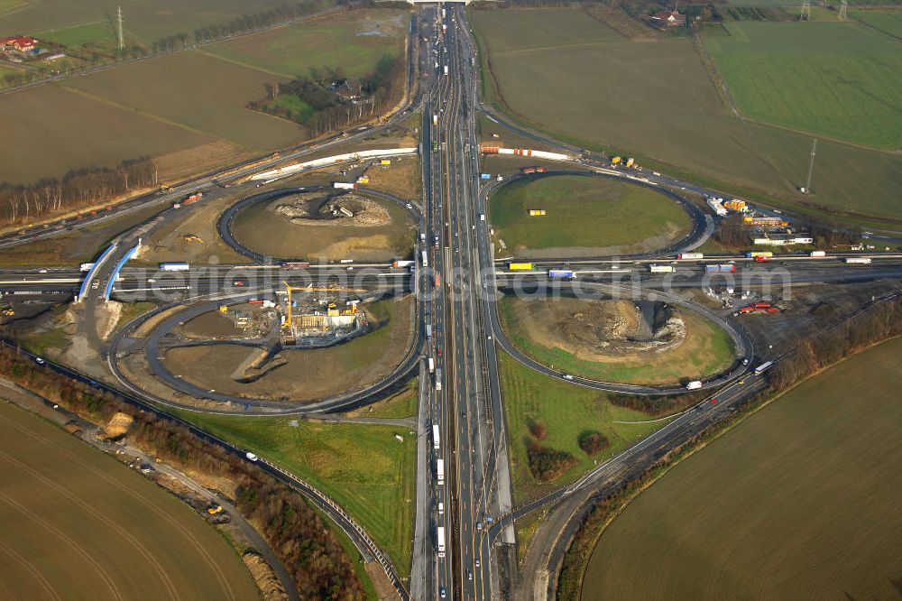 Aerial photograph Kamen - Das Kamener Kreuz ist das zweiteälteste Autobahnkreuz in Kleeblattform Deutschlands und dient der Verbindung der ersten Autobahnen des Landes, der A 1 (Nord-Süd-Richtung) und der A 2 (Ost-West-Richtung). Seine Einweihung fand 1937 statt. Das Autobahnkreuz liegt im Nordosten des Ruhrgebiets bei Kamen und Bergkamen zwischen den Großstädten Dortmund und Hamm und ist auch aufgrund der hier aufeinan dertreffenden wichtigen Verkehrsachsen ein überaus stark befahrener Verkehrsknotenpunkt. Die meisten Autofahrer kennen das Kamener Kreuz über die Staumeldungen der Verkehrsrundfunksender. Das Kamener Kreuz wird täglich von 160.000 Fahrzeugen befahren. Zur Zeit wird das Kamener Kreuz ausgebaut. Die Fertigstellung soll Ende 2009 sein. Das Kreuz wird dann von allen Seiten sechsspurig zu befahren sein. Eine besondere Herausforderung hierbei ist der Abriss und komplette Neubau der A 1-Brücke, die täglich von 90.000 Fahrzeugen befahren wird. Das Kreuz wird dann seine klassische Kleeblattform verlieren, da der Verkehr von der A 2 aus Richtung Hannover über eine Rampe auf die A 1 in Richtung Köln geleitet wird. Ausführende Firmen sind OEVERMANN, Münster Verkehrswegebau und Schäfer