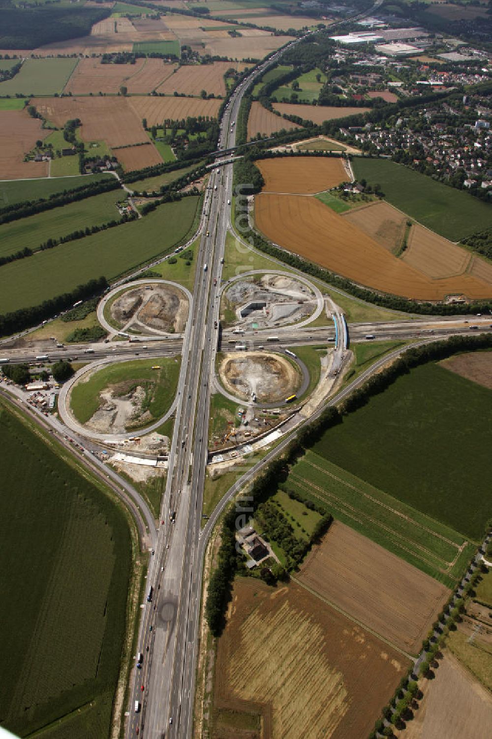 Aerial image Kamen - Das Kamener Kreuz ist das zweiteälteste Autobahnkreuz in Kleeblattform Deutschlands und dient der Verbindung der ersten Autobahnen des Landes, der A 1 (Nord-Süd-Richtung) und der A 2 (Ost-West-Richtung). Seine Einweihung fand 1937 statt. Das Autobahnkreuz liegt im Nordosten des Ruhrgebiets bei Kamen und Bergkamen zwischen den Großstädten Dortmund und Hamm und ist auch aufgrund der hier aufeinan dertreffenden wichtigen Verkehrsachsen ein überaus stark befahrener Verkehrsknotenpunkt. Die meisten Autofahrer kennen das Kamener Kreuz über die Staumeldungen der Verkehrsrundfunksender. Das Kamener Kreuz wird täglich von 160.000 Fahrzeugen befahren. Zur Zeit wird das Kamener Kreuz ausgebaut. Die Fertigstellung soll Ende 2009 sein. Das Kreuz wird dann von allen Seiten sechsspurig zu befahren sein. Eine besondere Herausforderung hierbei ist der Abriss und komplette Neubau der A 1-Brücke, die täglich von 90.000 Fahrzeugen befahren wird. Das Kreuz wird dann seine klassische Kleeblattform verlieren, da der Verkehr von der A 2 aus Richtung Hannover über eine Rampe auf die A 1 in Richtung Köln geleitet wird. Ausführende Firmen sind OEVERMANN, Münster Verkehrswegebau und Schäfer