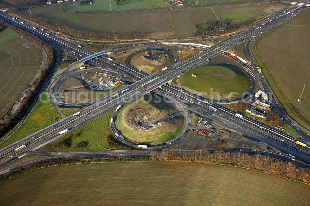 Aerial photograph Kamen - Das Kamener Kreuz ist das zweiteälteste Autobahnkreuz in Kleeblattform Deutschlands und dient der Verbindung der ersten Autobahnen des Landes, der A 1 (Nord-Süd-Richtung) und der A 2 (Ost-West-Richtung). Seine Einweihung fand 1937 statt. Das Autobahnkreuz liegt im Nordosten des Ruhrgebiets bei Kamen und Bergkamen zwischen den Großstädten Dortmund und Hamm und ist auch aufgrund der hier aufeinan dertreffenden wichtigen Verkehrsachsen ein überaus stark befahrener Verkehrsknotenpunkt. Die meisten Autofahrer kennen das Kamener Kreuz über die Staumeldungen der Verkehrsrundfunksender. Das Kamener Kreuz wird täglich von 160.000 Fahrzeugen befahren. Zur Zeit wird das Kamener Kreuz ausgebaut. Die Fertigstellung soll Ende 2009 sein. Das Kreuz wird dann von allen Seiten sechsspurig zu befahren sein. Eine besondere Herausforderung hierbei ist der Abriss und komplette Neubau der A 1-Brücke, die täglich von 90.000 Fahrzeugen befahren wird. Das Kreuz wird dann seine klassische Kleeblattform verlieren, da der Verkehr von der A 2 aus Richtung Hannover über eine Rampe auf die A 1 in Richtung Köln geleitet wird. Ausführende Firmen sind OEVERMANN, Münster Verkehrswegebau und Schäfer