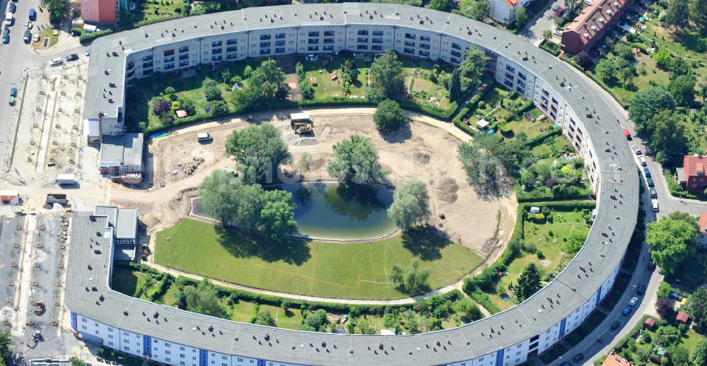 Aerial image Berlin Britz - Blick auf die Hufeisensiedlung in Britz. Derzeit laufen umfangreiche Grünflächenumgestaltungsarbeiten rund um den Hufeisenteich an der Mittelinsel Hüsung. Das Landesdenkmalamt verfolgt mit der umstrittenen Umgestaltung das Ziel, das ursprüngliche Erscheinungsbild von 1930 nach den Plänen der Architekten Taut/Wagner wieder herzustellen. Das Wohngebiet Hufeisensiedlung ist 2008 als Siedlung der Berliner Moderne von der UNESCO in die Liste des Welterbes aufgenommen worden. Die Großsiedlung Britz, nach der zentralen Baugruppe Hufeisensiedlung genannt, entstand 1925 -33 (in sieben Bauabschnitten) nach Plänen von Bruno Taut. The residential area Hufeisensiedlung in Berlin Britz.