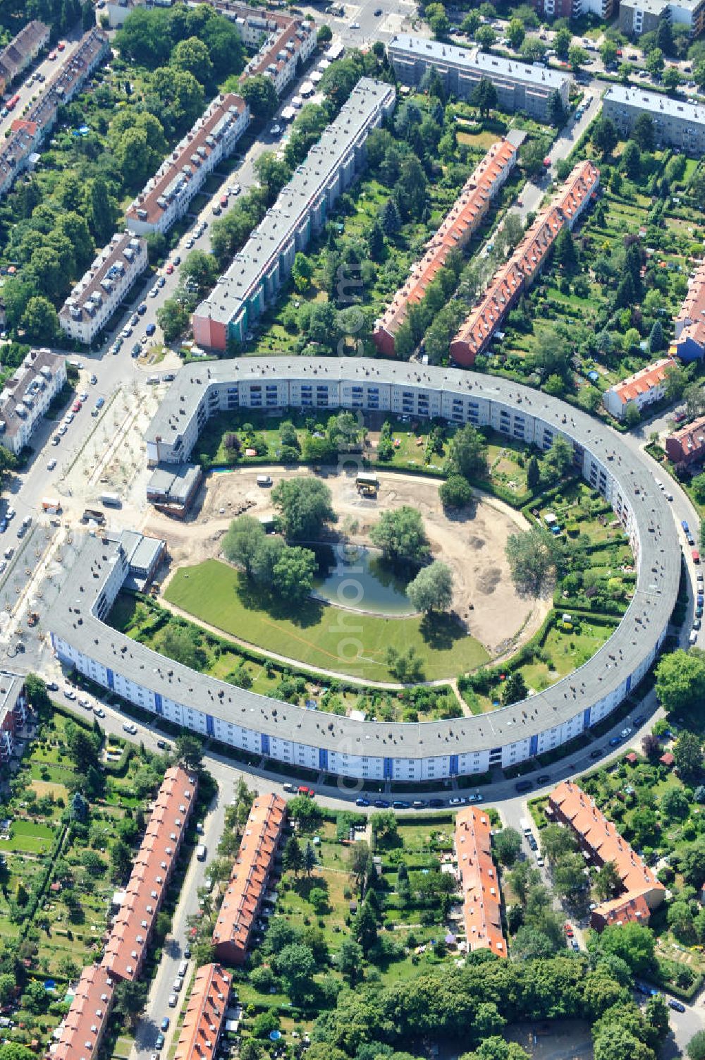 Berlin Britz from above - Blick auf die Hufeisensiedlung in Britz. Derzeit laufen umfangreiche Grünflächenumgestaltungsarbeiten rund um den Hufeisenteich an der Mittelinsel Hüsung. Das Landesdenkmalamt verfolgt mit der umstrittenen Umgestaltung das Ziel, das ursprüngliche Erscheinungsbild von 1930 nach den Plänen der Architekten Taut/Wagner wieder herzustellen. Das Wohngebiet Hufeisensiedlung ist 2008 als Siedlung der Berliner Moderne von der UNESCO in die Liste des Welterbes aufgenommen worden. Die Großsiedlung Britz, nach der zentralen Baugruppe Hufeisensiedlung genannt, entstand 1925 -33 (in sieben Bauabschnitten) nach Plänen von Bruno Taut. The residential area Hufeisensiedlung in Berlin Britz.