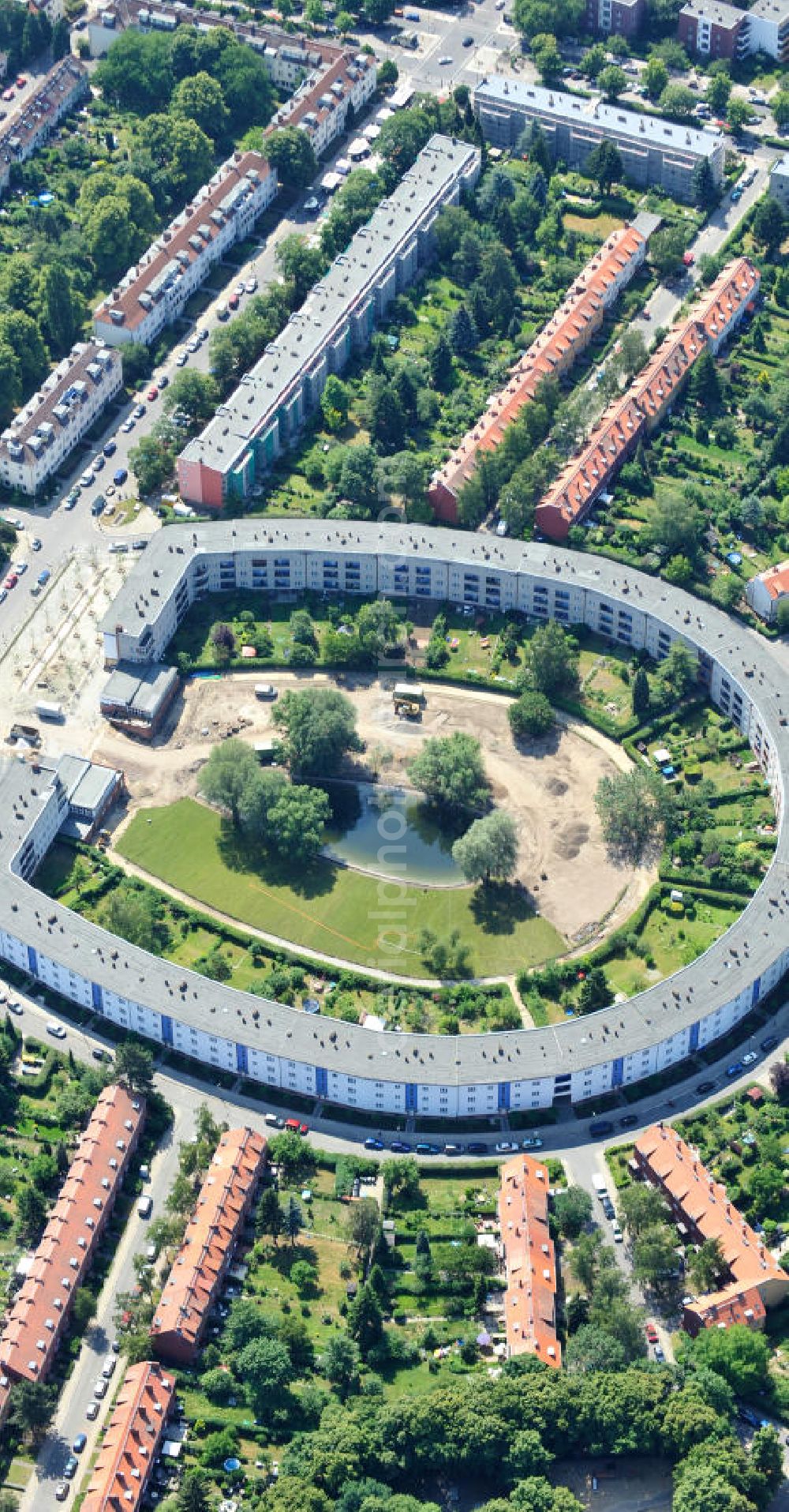 Berlin Britz from the bird's eye view: Blick auf die Hufeisensiedlung in Britz. Derzeit laufen umfangreiche Grünflächenumgestaltungsarbeiten rund um den Hufeisenteich an der Mittelinsel Hüsung. Das Landesdenkmalamt verfolgt mit der umstrittenen Umgestaltung das Ziel, das ursprüngliche Erscheinungsbild von 1930 nach den Plänen der Architekten Taut/Wagner wieder herzustellen. Das Wohngebiet Hufeisensiedlung ist 2008 als Siedlung der Berliner Moderne von der UNESCO in die Liste des Welterbes aufgenommen worden. Die Großsiedlung Britz, nach der zentralen Baugruppe Hufeisensiedlung genannt, entstand 1925 -33 (in sieben Bauabschnitten) nach Plänen von Bruno Taut. The residential area Hufeisensiedlung in Berlin Britz.