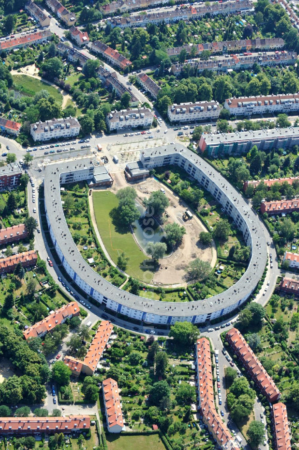 Aerial image Berlin Britz - Blick auf die Hufeisensiedlung in Britz. Derzeit laufen umfangreiche Grünflächenumgestaltungsarbeiten rund um den Hufeisenteich an der Mittelinsel Hüsung. Das Landesdenkmalamt verfolgt mit der umstrittenen Umgestaltung das Ziel, das ursprüngliche Erscheinungsbild von 1930 nach den Plänen der Architekten Taut/Wagner wieder herzustellen. Das Wohngebiet Hufeisensiedlung ist 2008 als Siedlung der Berliner Moderne von der UNESCO in die Liste des Welterbes aufgenommen worden. Die Großsiedlung Britz, nach der zentralen Baugruppe Hufeisensiedlung genannt, entstand 1925 -33 (in sieben Bauabschnitten) nach Plänen von Bruno Taut. The residential area Hufeisensiedlung in Berlin Britz.