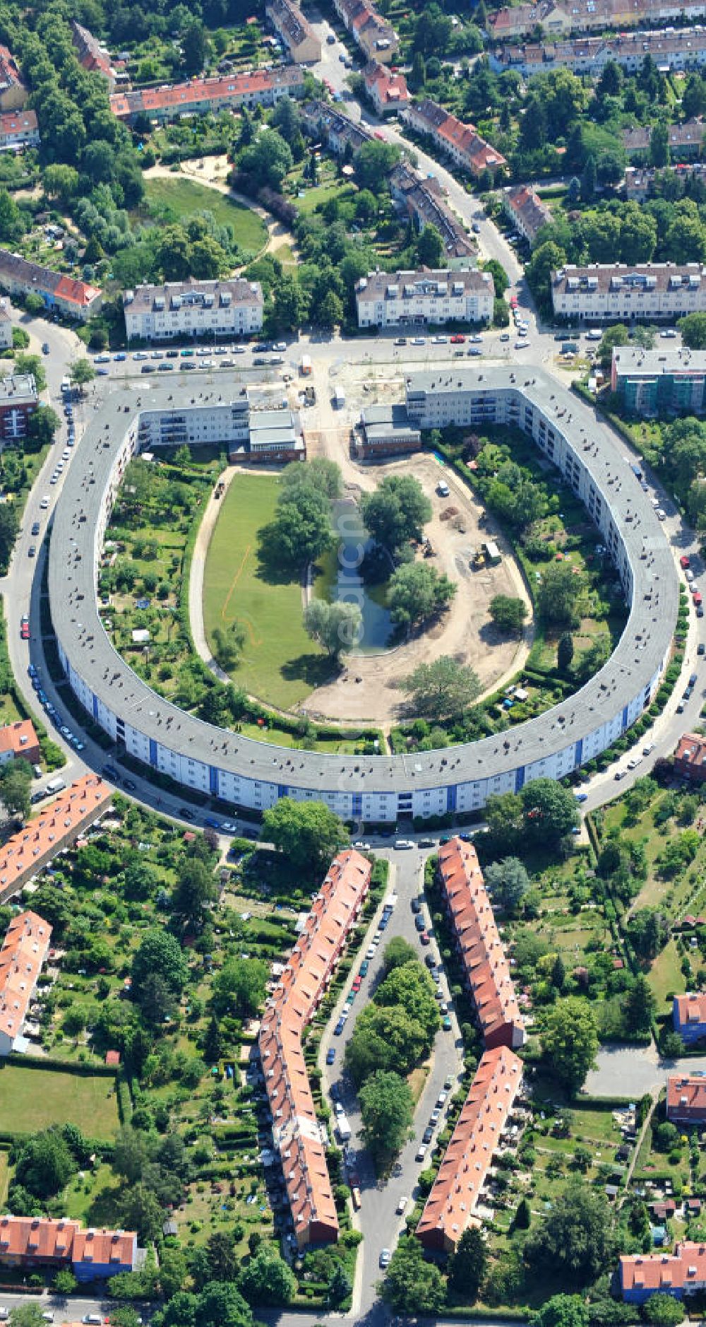 Aerial photograph Berlin Britz - Blick auf die Hufeisensiedlung in Britz. Derzeit laufen umfangreiche Grünflächenumgestaltungsarbeiten rund um den Hufeisenteich an der Mittelinsel Hüsung. Das Landesdenkmalamt verfolgt mit der umstrittenen Umgestaltung das Ziel, das ursprüngliche Erscheinungsbild von 1930 nach den Plänen der Architekten Taut/Wagner wieder herzustellen. Das Wohngebiet Hufeisensiedlung ist 2008 als Siedlung der Berliner Moderne von der UNESCO in die Liste des Welterbes aufgenommen worden. Die Großsiedlung Britz, nach der zentralen Baugruppe Hufeisensiedlung genannt, entstand 1925 -33 (in sieben Bauabschnitten) nach Plänen von Bruno Taut. The residential area Hufeisensiedlung in Berlin Britz.