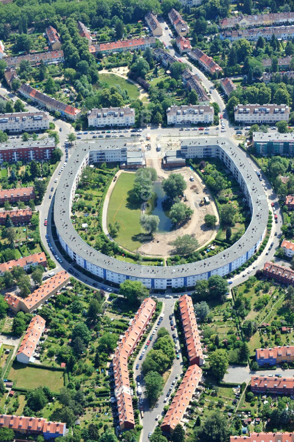 Berlin Britz from above - Blick auf die Hufeisensiedlung in Britz. Derzeit laufen umfangreiche Grünflächenumgestaltungsarbeiten rund um den Hufeisenteich an der Mittelinsel Hüsung. Das Landesdenkmalamt verfolgt mit der umstrittenen Umgestaltung das Ziel, das ursprüngliche Erscheinungsbild von 1930 nach den Plänen der Architekten Taut/Wagner wieder herzustellen. Das Wohngebiet Hufeisensiedlung ist 2008 als Siedlung der Berliner Moderne von der UNESCO in die Liste des Welterbes aufgenommen worden. Die Großsiedlung Britz, nach der zentralen Baugruppe Hufeisensiedlung genannt, entstand 1925 -33 (in sieben Bauabschnitten) nach Plänen von Bruno Taut. The residential area Hufeisensiedlung in Berlin Britz.