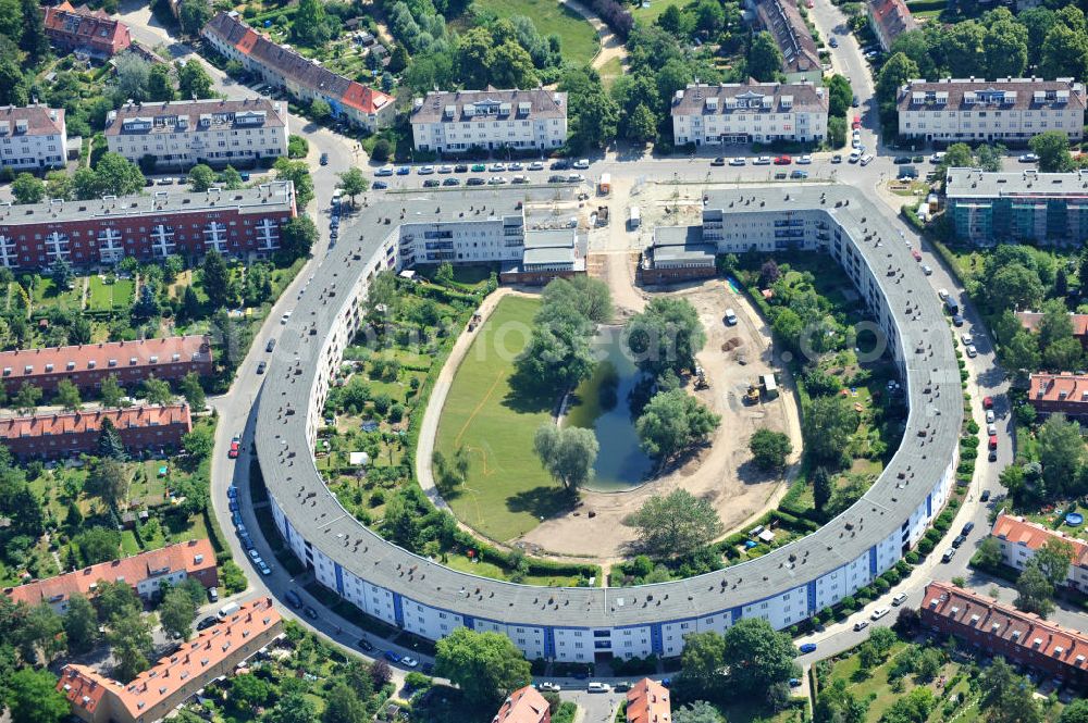 Berlin Britz from the bird's eye view: Blick auf die Hufeisensiedlung in Britz. Derzeit laufen umfangreiche Grünflächenumgestaltungsarbeiten rund um den Hufeisenteich an der Mittelinsel Hüsung. Das Landesdenkmalamt verfolgt mit der umstrittenen Umgestaltung das Ziel, das ursprüngliche Erscheinungsbild von 1930 nach den Plänen der Architekten Taut/Wagner wieder herzustellen. Das Wohngebiet Hufeisensiedlung ist 2008 als Siedlung der Berliner Moderne von der UNESCO in die Liste des Welterbes aufgenommen worden. Die Großsiedlung Britz, nach der zentralen Baugruppe Hufeisensiedlung genannt, entstand 1925 -33 (in sieben Bauabschnitten) nach Plänen von Bruno Taut. The residential area Hufeisensiedlung in Berlin Britz.