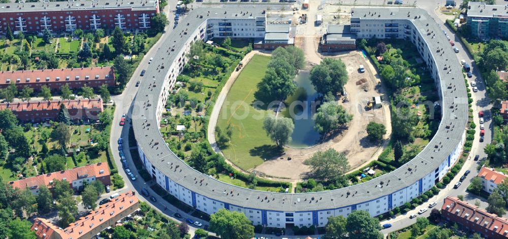 Aerial image Berlin Britz - Blick auf die Hufeisensiedlung in Britz. Derzeit laufen umfangreiche Grünflächenumgestaltungsarbeiten rund um den Hufeisenteich an der Mittelinsel Hüsung. Das Landesdenkmalamt verfolgt mit der umstrittenen Umgestaltung das Ziel, das ursprüngliche Erscheinungsbild von 1930 nach den Plänen der Architekten Taut/Wagner wieder herzustellen. Das Wohngebiet Hufeisensiedlung ist 2008 als Siedlung der Berliner Moderne von der UNESCO in die Liste des Welterbes aufgenommen worden. Die Großsiedlung Britz, nach der zentralen Baugruppe Hufeisensiedlung genannt, entstand 1925 -33 (in sieben Bauabschnitten) nach Plänen von Bruno Taut. The residential area Hufeisensiedlung in Berlin Britz.