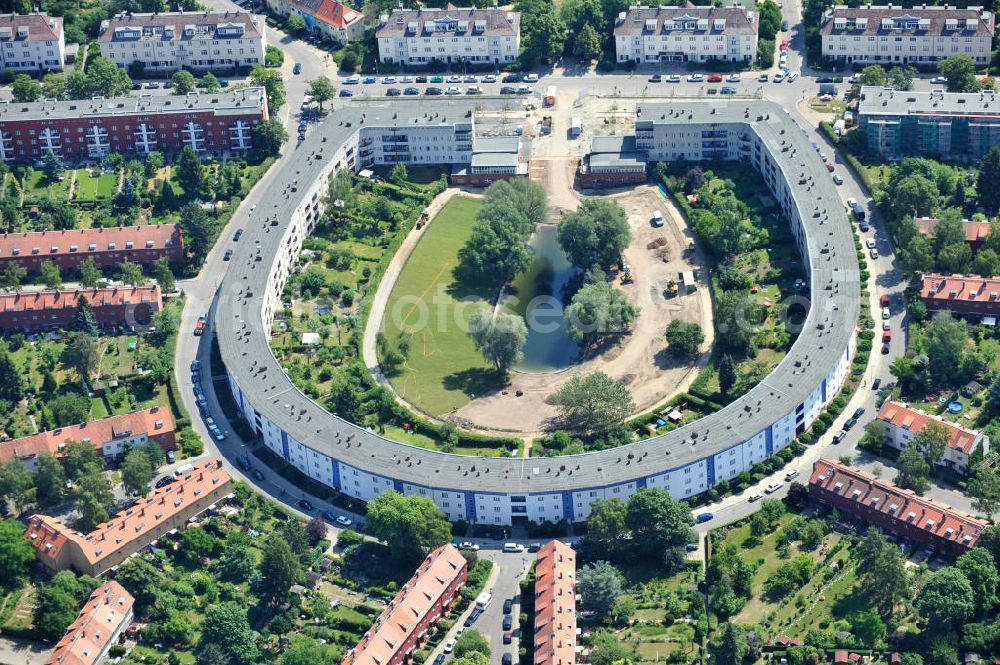 Aerial photograph Berlin Britz - Blick auf die Hufeisensiedlung in Britz. Derzeit laufen umfangreiche Grünflächenumgestaltungsarbeiten rund um den Hufeisenteich an der Mittelinsel Hüsung. Das Landesdenkmalamt verfolgt mit der umstrittenen Umgestaltung das Ziel, das ursprüngliche Erscheinungsbild von 1930 nach den Plänen der Architekten Taut/Wagner wieder herzustellen. Das Wohngebiet Hufeisensiedlung ist 2008 als Siedlung der Berliner Moderne von der UNESCO in die Liste des Welterbes aufgenommen worden. Die Großsiedlung Britz, nach der zentralen Baugruppe Hufeisensiedlung genannt, entstand 1925 -33 (in sieben Bauabschnitten) nach Plänen von Bruno Taut. The residential area Hufeisensiedlung in Berlin Britz.