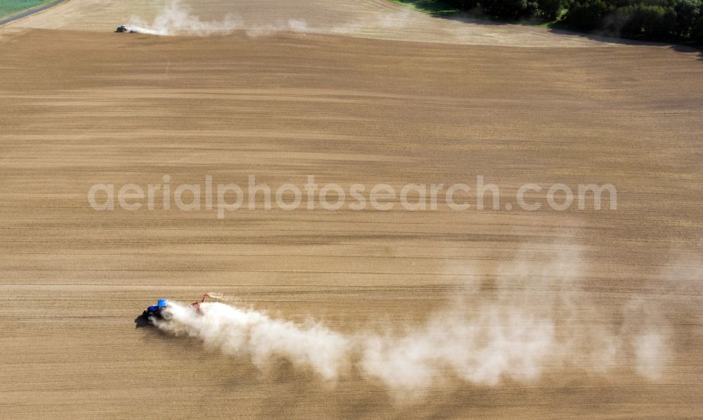 Grimma from the bird's eye view: Plowing and shifting the earth by a tractor with plow on agricultural fields in Grimma in the state Saxony, Germany