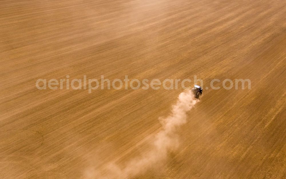 Aerial photograph Grimma - Plowing and shifting the earth by a tractor with plow on agricultural fields in Grimma in the state Saxony, Germany