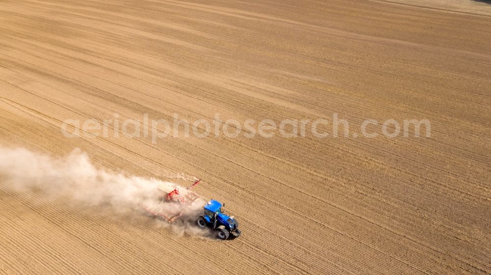 Aerial image Grimma - Plowing and shifting the earth by a tractor with plow on agricultural fields in Grimma in the state Saxony, Germany