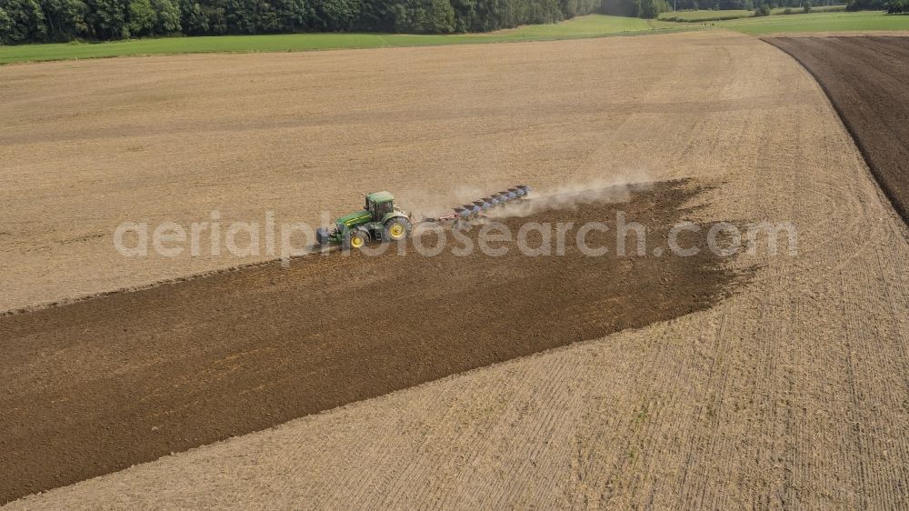 Aerial photograph Sauheim - Plowing and shifting the earth by a tractor with plow on agricultural fields in Sauheim in the state Bavaria