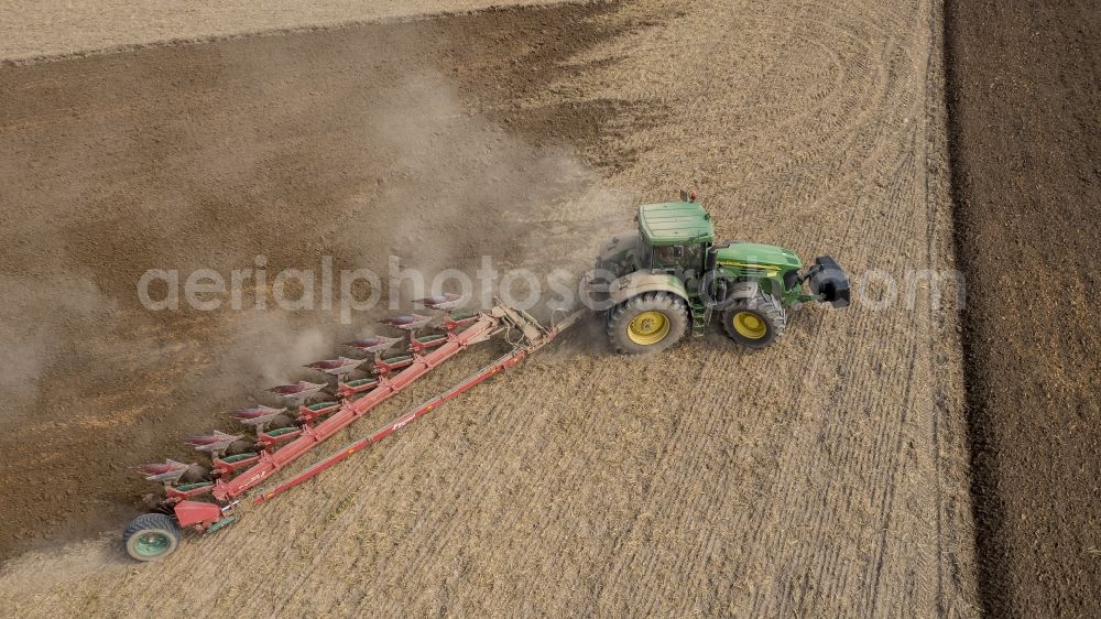 Sauheim from above - Plowing and shifting the earth by a tractor with plow on agricultural fields in Sauheim in the state Bavaria