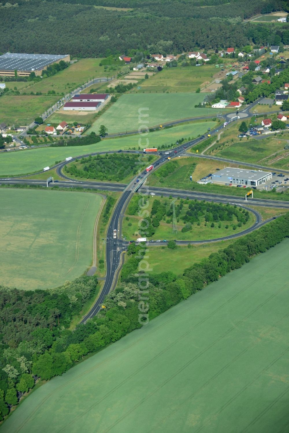 Blankenfelde-Mahlow from the bird's eye view: Traffic flow at the intersection of the federal highway B96 and county road L40 in Blankenfelde-Mahlow in the state of Brandenburg. The two roads are connected via the interchange amidst fields and meadows. A building of Automobil Group Ost AG is located in one of the bends of the clover leaf interchange