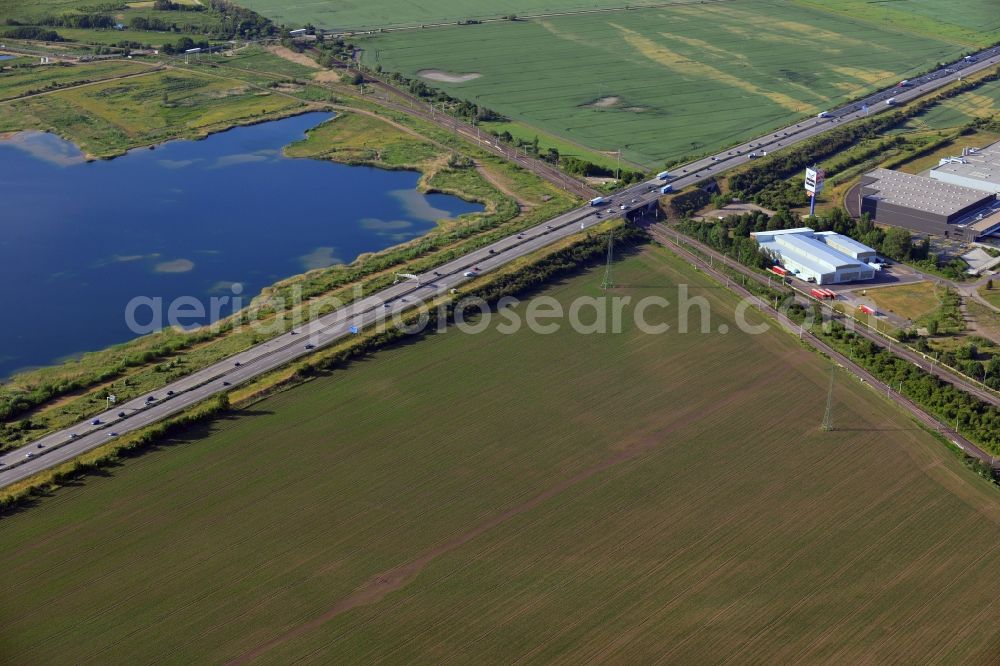 Magdeburg from the bird's eye view: Course of the A2, lake Adamsee and fields in the North of Magdeburg in the state of Saxony-Anhalt. A commercial area is located along the federal motorway A2 which takes its course through fields and along the lake