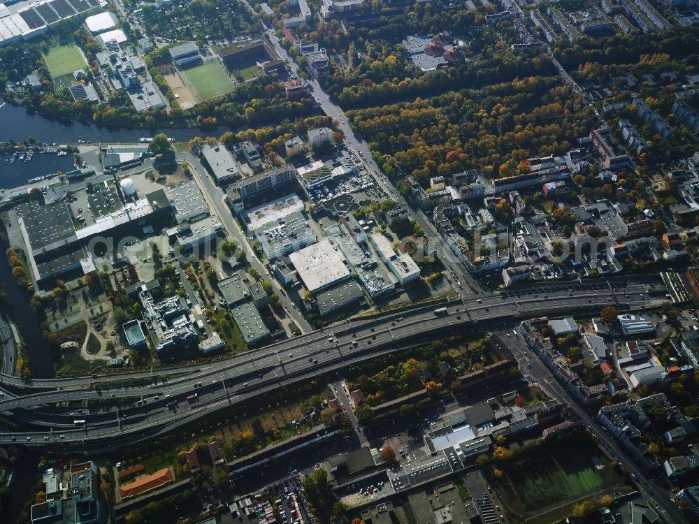 Berlin from the bird's eye view: Course of the federal motorway A100 and A113 in the area of the exit Grenzallee in the Neukoelln part of Berlin in Germany. The A100 joins the A113 towards the South. The motorway passes the harbour of Britz-East in the area which mainly consists of company compounds and commercial areas