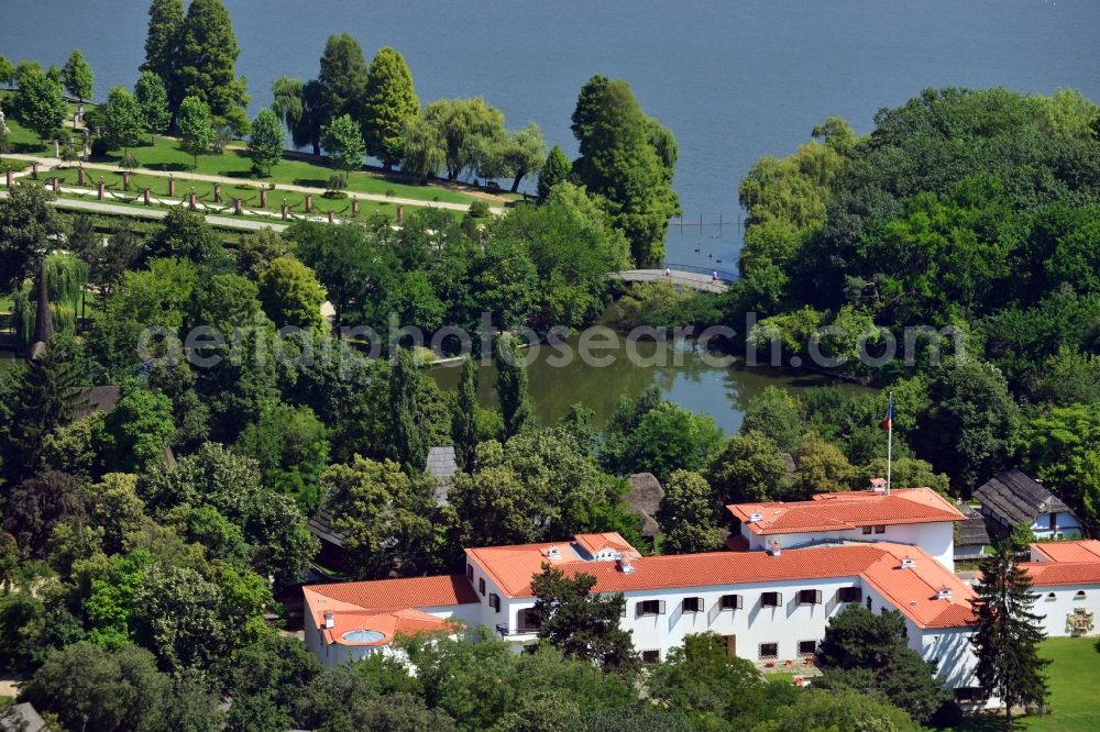 Bukarest from the bird's eye view: Villa on lake Lacul Herastrau near the island Insula Tradafirilor in Sector 1 in Bucharest in Romania. The compound is located on the shore of the lake and surrounded by forest. It is built in a cottage style with distinct orange roofs