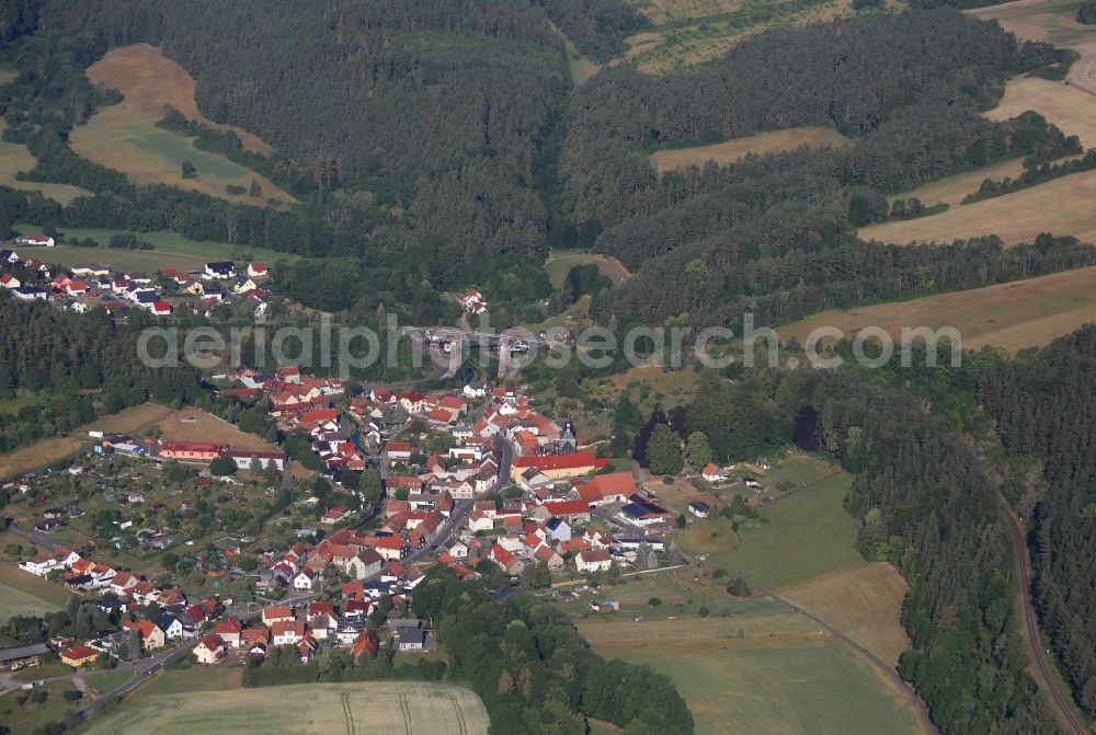 Angelroda from above - Surrounded by forest and forest areas center of the streets and houses and residential areas in Angelroda in the state Thuringia, Germany