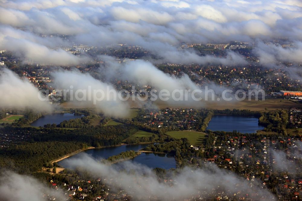 Berlin from the bird's eye view: View of clouds circling the countryside surrounding the three Kaulsdorfer Lakes Butzer See, Elsensee and Habermannsee in Berlin - Kaulsdorf. The lakes are located in a nature preserve surrounded by localities with small houses