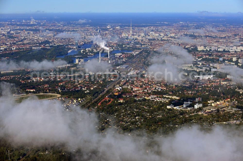 Aerial image Berlin - Cityscape traversed by clouds overlooking the districts of Karlshorst, Rummelsburg and Oberschoeneweide along the S-Bahn tracks and Spree route in direction of the television tower in Berlin