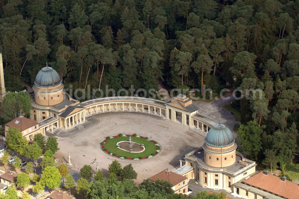 Darmstadt from the bird's eye view: Der Waldfriedhof Darmstadt wurde zu Beginn des ersten Weltkrieges in Darmstadt angelegt. Er liegt in einem Waldstück am westlichen Stadtrand von Darmstadt. Die Pläne zu der markanten, hufeisenförmigen Anlage stammen von August Buxbaum. Als erstes Gebäude entstand das Krematorium 1913 bis 1914. Der Waldfriedhof wurde 1914 eingeweiht. Nach Verzögerungen durch den ersten Weltkrieg wurden die Aussegnungs- und Leichenhalle erst 1918 fertig, der Rest der Friedhofsgebäude folgte bis 1922. Von besonderem Eindruck im Waldfriedhof sind das Ehrenmal und die Gedenkstätte für die Toten beider Weltkriege. Innerhalb des weiträumigen Ehrenmales musste ein Massengrab für die etwa 12.000 in der Brandnacht am 11. September 1944 umgekommenen Darmstädter Bürgerinnen und Bürger angelegt werden, die vielfach nicht mehr identifizierbar waren. Das Areal ist als Rondell ausgebildet. Auf Bronzetafeln an der Mauer des unteren Umgangs sind die Namen der Toten verzeichnet.