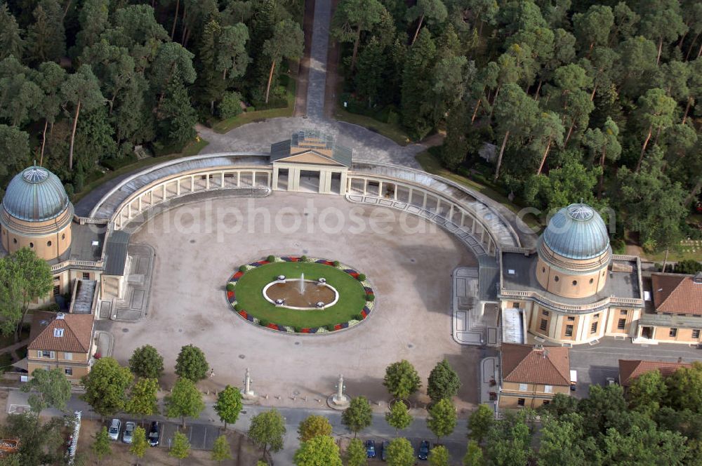 Aerial photograph Darmstadt - Der Waldfriedhof Darmstadt wurde zu Beginn des ersten Weltkrieges in Darmstadt angelegt. Er liegt in einem Waldstück am westlichen Stadtrand von Darmstadt. Die Pläne zu der markanten, hufeisenförmigen Anlage stammen von August Buxbaum. Als erstes Gebäude entstand das Krematorium 1913 bis 1914. Der Waldfriedhof wurde 1914 eingeweiht. Nach Verzögerungen durch den ersten Weltkrieg wurden die Aussegnungs- und Leichenhalle erst 1918 fertig, der Rest der Friedhofsgebäude folgte bis 1922. Von besonderem Eindruck im Waldfriedhof sind das Ehrenmal und die Gedenkstätte für die Toten beider Weltkriege. Innerhalb des weiträumigen Ehrenmales musste ein Massengrab für die etwa 12.000 in der Brandnacht am 11. September 1944 umgekommenen Darmstädter Bürgerinnen und Bürger angelegt werden, die vielfach nicht mehr identifizierbar waren. Das Areal ist als Rondell ausgebildet. Auf Bronzetafeln an der Mauer des unteren Umgangs sind die Namen der Toten verzeichnet.