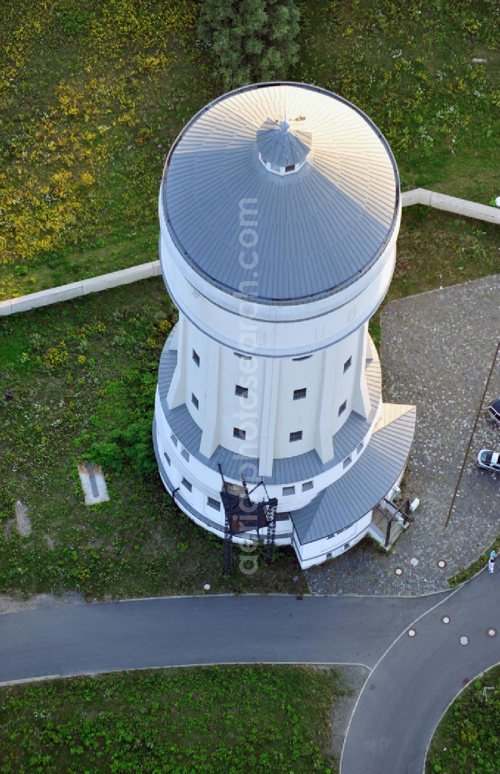 Aerial image Eilenburg - Der etwa 60 Meter hohe Wasserturm in Eilenburg-Ost in Sachsen wurde 1916 in der aufwendigen Bauart Otto Intzes vom Unternehmen Dyckerhoff und Widmann AG für die große Zelluloidfabrik gebaut. Nachdem er in der Zeit der DDR immer mehr verfallen war, wurde er im Jahr 2002 wieder instandgesetzt. Der Turm dient nun als Löschwasserspeicher für das benachbarte Industrie- und Gewerbegebiet Kunstoffcenter am ECW-Wasserturm und gilt als das wohl eindrucksvollste technische Denkmal der Stadt. About 60 metres high water tower in Eilenburg-East in Saxony was build 1916 in elaborate style of Otto Intzes by company Dyckerhoff und Widmann AG for a big celluloid factory. Gone to rack during the time of DDR, the tower was refurbished in 2002. It now serves as a fire water reservoir for industrial area Kunstoffcenter am ECW-Wasserturm nearby and is regarded as the most impressive technical monument of the town.