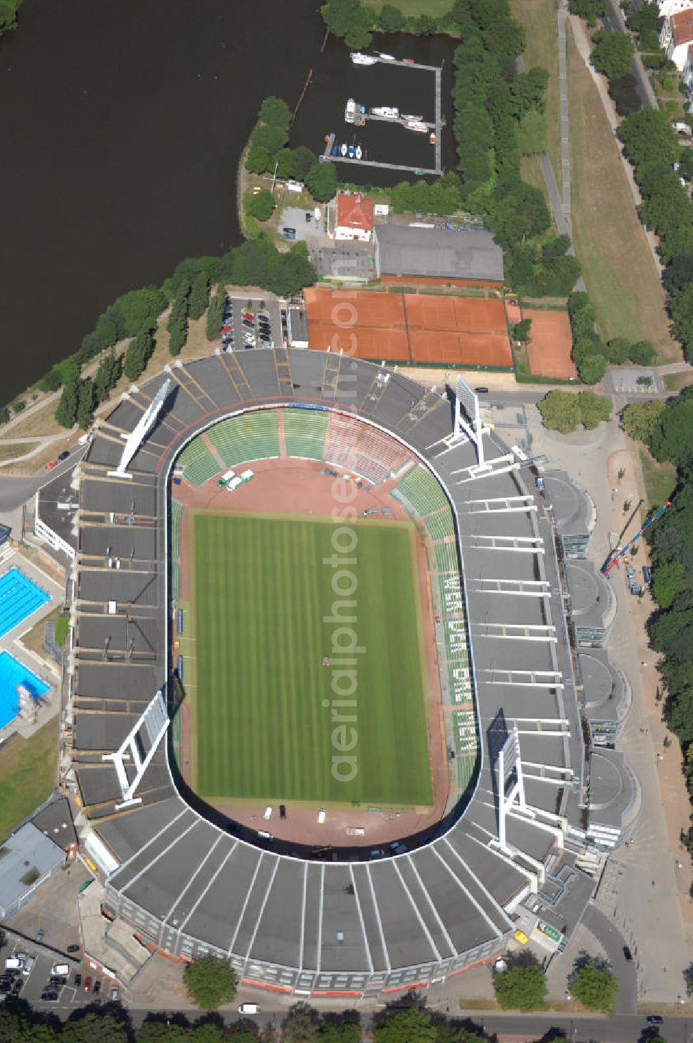 BREMEN from the bird's eye view: Das Weserstadion in Bremen ist das Stadion des deutschen Fußball-Bundesligisten Werder Bremen. Es liegt direkt an der Weser, am rechten Weserufer, in der Pauliner Marsch, einem Überflutungsgebiet vor dem Osterdeich im Stadtteil Östliche Vorstadt, Ortsteil Peterswerder.Das Bremer Weserstadion wurde 1909 vom Allgemeinen Bremer Turn- und Sportverein als Sportplatz erbaut und nach seinem ersten Umbau im Jahre 1926 ABTS-Kampfbahn benannt. Der heutige Name, der auf die unmittelbare Lage an der Weser zurückgeht, besteht seit 1930. Seit dieser Zeit trägt dort auch der SV Werder Bremen seine Spiele aus. Auch der Bremer Sport-Verein von 1906 trug im Weserstadion seine Oberligaspiele bis 1963 aus. Zu Beginn der ersten Saison der Fußball-Bundesliga (1963) erhielt das Stadion seine erste überdachte Tribüne. In den folgenden Jahrzehnten wurden auch die an deren Tribünen erbaut und sukzessive modernisiert. 1992 wurde erstmals in einem Stadion eine VIP-Loge eingeführt. Im Jahr 2009 ist der Umbau des Weserstadions zu einem reinen Fußballstadion geplant. Bremer Weser-Stadion GmbH, Franz-Böhmert-Str. 7 , 28205 Bremen,Tel.: 0421 / 49 131 10