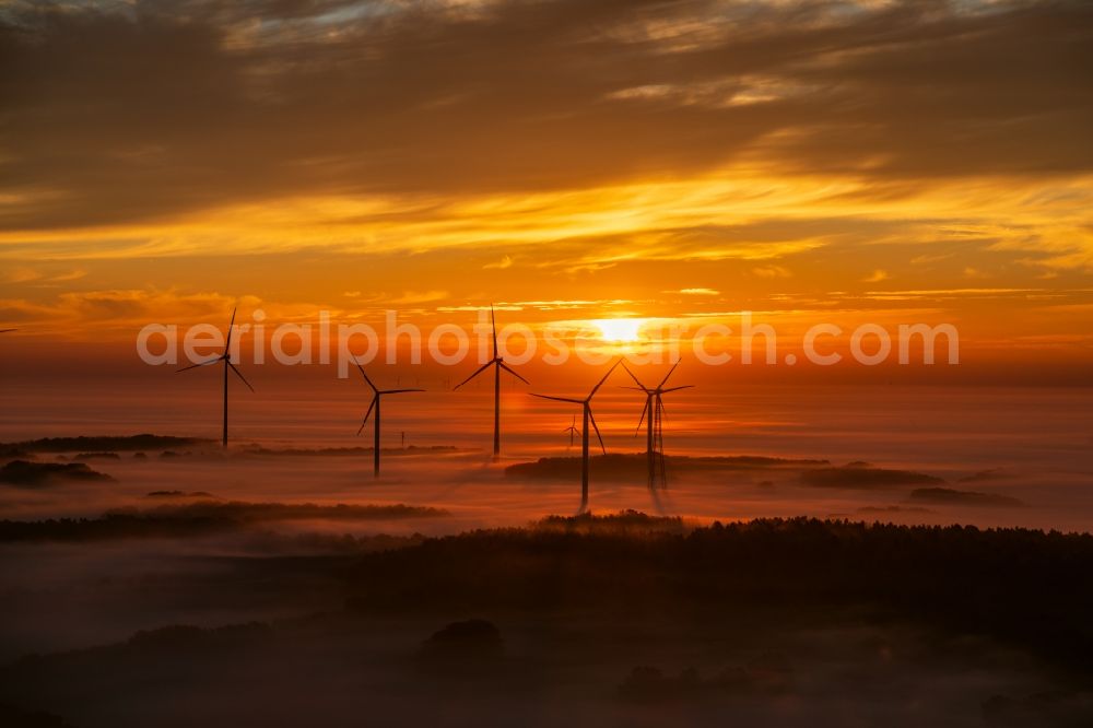 Winsen (Luhe) from the bird's eye view: Weather-induced wind energy installations embedded in a fog layer at sunrise in Winsen (Luhe) in the state Lower Saxony, Germany