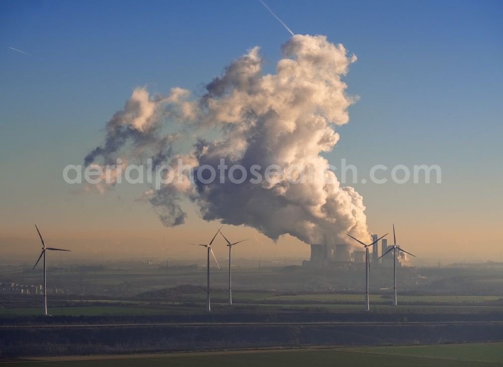 Aerial photograph Grevenbroich - Wind turbine windmills on a field in the district Frimmersdorf in Grevenbroich in the state North Rhine-Westphalia. In the background, the exhaust gas clouds in the sky above the brown coal power station - Kraftwerk Frimmersdorf of RWE Power