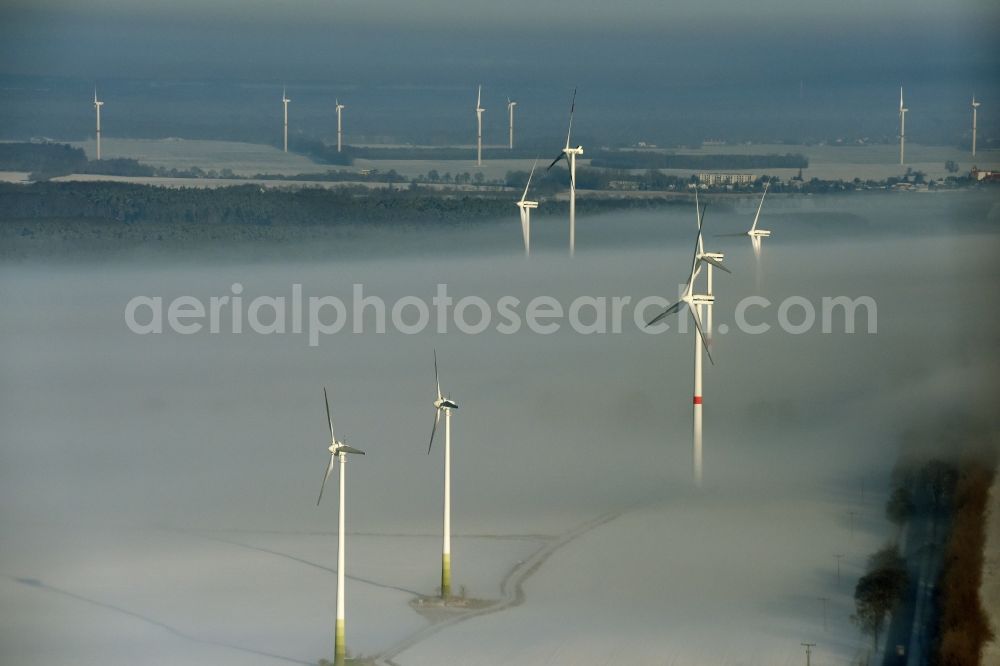 Werneuchen from the bird's eye view: Wind turbine windmills on a winterly snow and fog covered field in Werneuchen in the state of Brandenburg