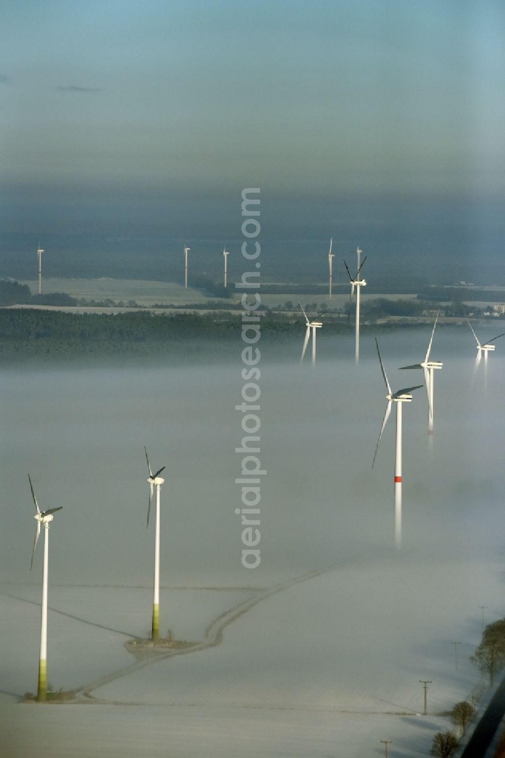 Aerial photograph Werneuchen - Wind turbine windmills on a winterly snow and fog covered field in Werneuchen in the state of Brandenburg