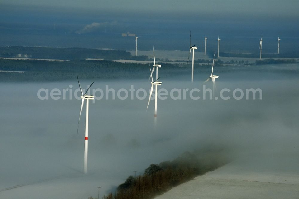 Werneuchen from the bird's eye view: Wind turbine windmills on a winterly snow and fog covered field in Werneuchen in the state of Brandenburg