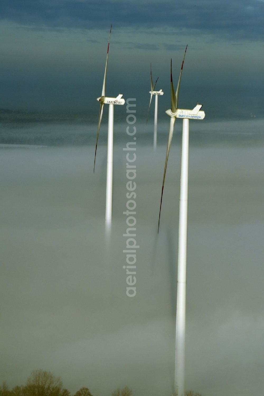 Werneuchen from above - Wind turbine windmills of Notus, Saxovent and Stahl Energy on a winterly snow and fog covered field in Werneuchen in the state of Brandenburg