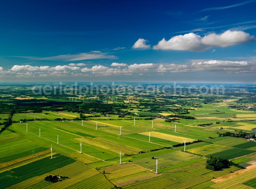 Wilster from the bird's eye view: Wind power wheels and turbines in the county district of Steinburg in the state of Schleswig-Holstein. The turbines are placed between fields. Overview of the agricultural structures as well as the wheels used to create energy