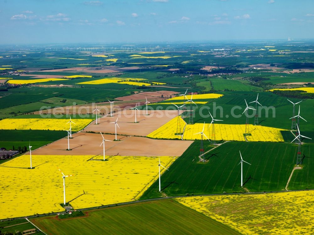 Frauenprießnitz from above - Wind power wheels and turbines in the county district of Frauenprießnitz in the community of Dornburg-Camburg in the state of Thüringen. The turbines are placed between canola and other fields. Overview of the agricultural structures as well as the wheels used to create energy. The purification plant of Frauenprießnitz is visible as well