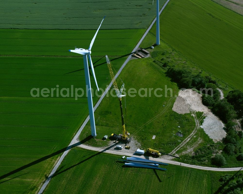 Aerial photograph Dithmarschen - Wind power wheels and turbines in the county district of Düren in the state of North Rhine-Westphalia. The turbines are placed between fields and are being built. Overview of the agricultural structures as well as the wheels used to create energy as well as the weels and turbines