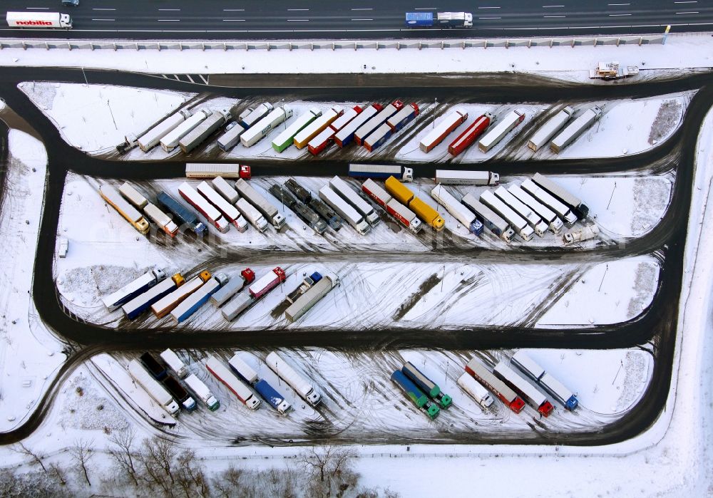 Hamm from the bird's eye view: Winter - landscape of snow-covered truck parking at the rest area Hamm, a welcome for driving periods - used breaks in freight resting place in Hamm in North Rhine-Westphalia