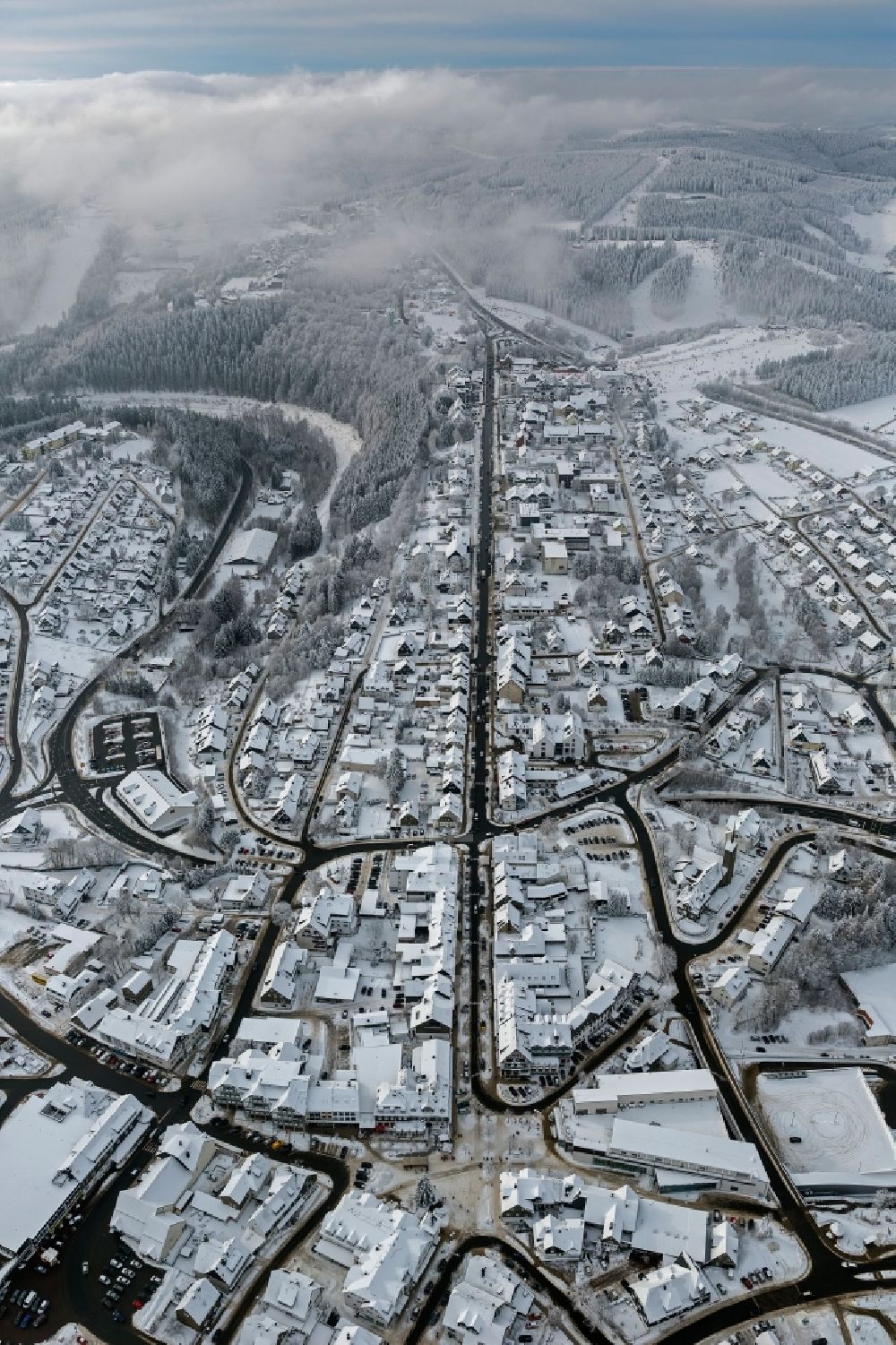 Winterberg from the bird's eye view: Winter city view from the snow-covered city center to the tourist center Oversum in Winterberg in North Rhine-Westphalia NRW. The Oversum Vital Resort Winterberg is a hotel - complex with gym and spa