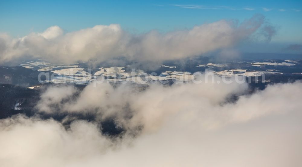 Aerial image Winterberg - View of the snow-covered landscape of Winterberg, which is surrounded by clouds and haze and is located in the district Hochsauerlandkreis HSK in the state North Rhine-Westphalia