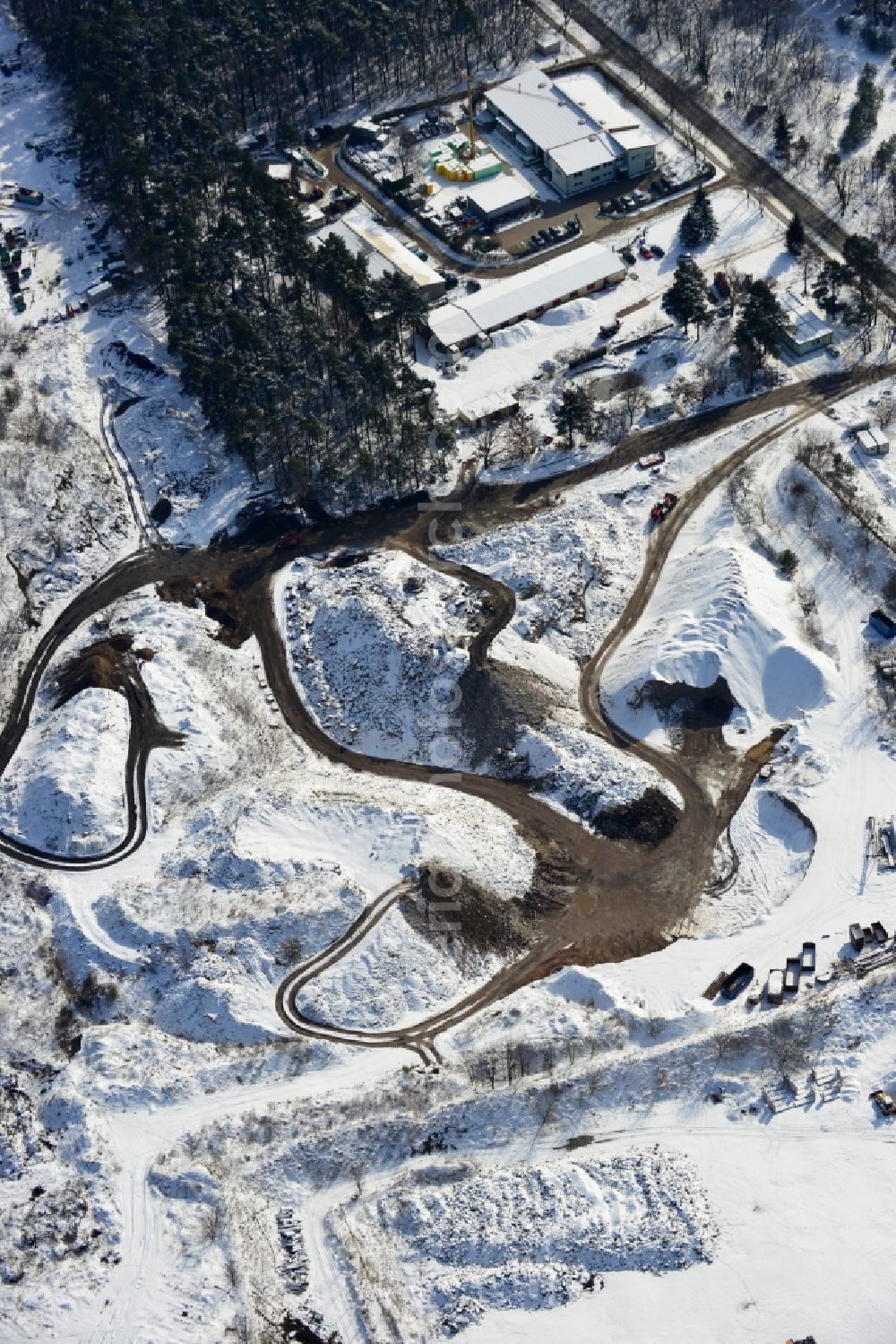 Berlin from above - Wintry road covered with snow the recycling of building materials and soil treatment company in the cemetery road Berlin - Mahlsdorf