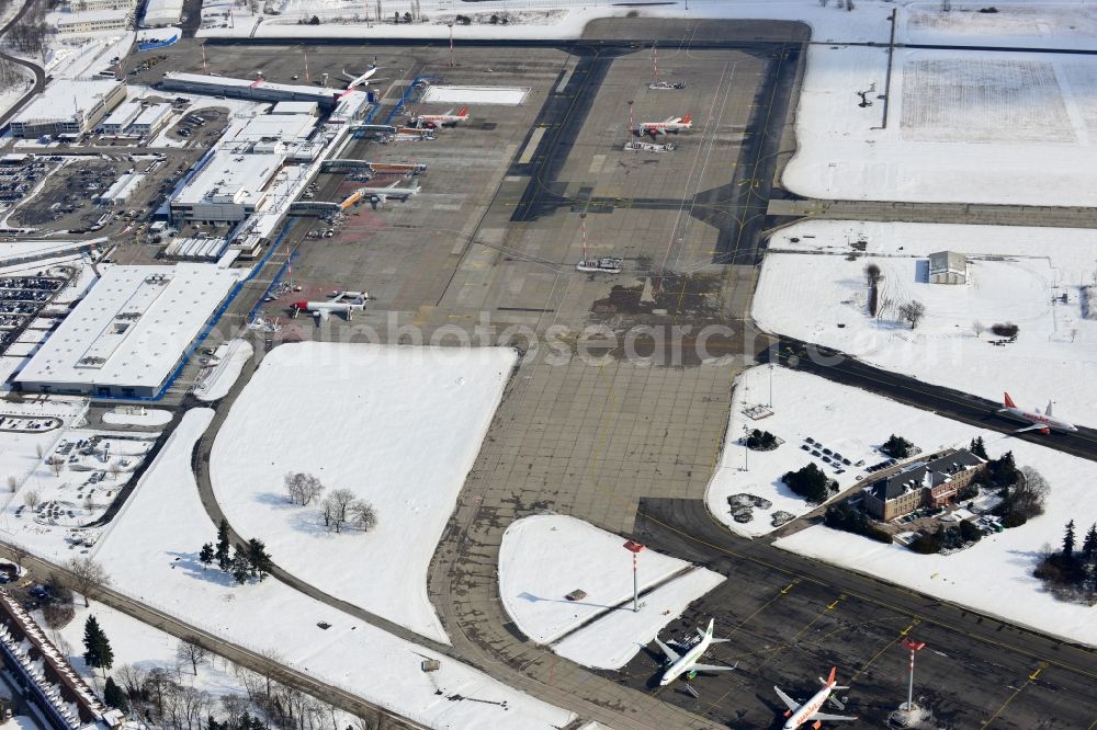 Schönefeld from the bird's eye view: Winter covered with snow runways, taxiways, terminal building and old DDR terminal from INTERFLUG times at Berlin - Schonefeld